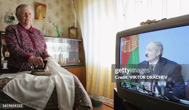 Woman irons clothes, as Belarus President Alexander Lukashenko holds a press conference in Minsk, 20 March 2006. The election that swept Belarussian...