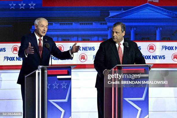 Former Governor of Arkansas Asa Hutchinson speaks flanked by former Governor of New Jersey Chris Christie speaks during the first Republican...