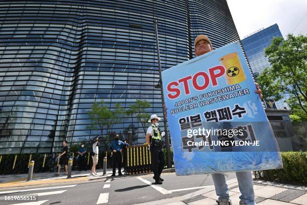 South Korean man holds a placard in front of a building housing the Japanese embassy in Seoul on August 24 as South Korean protesters gather to...