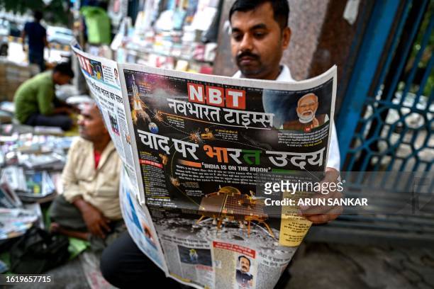 Man reads a daily hindi newspaper with front page reporting on successful landing of ISRO's Chandrayaan-3 spacecraft on the south pole of the Moon,...