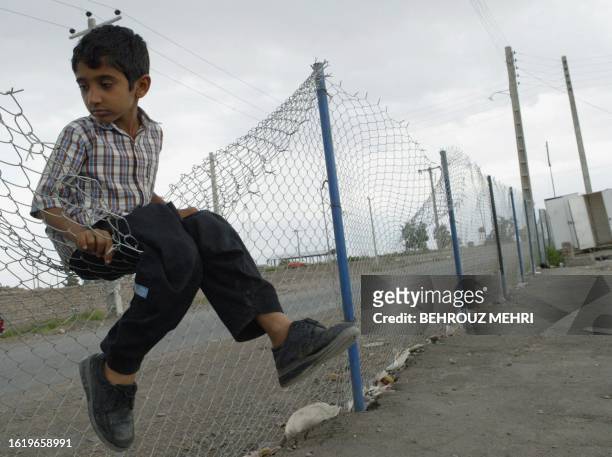 An Iranian boy sits on a fence in a makeshift housing camp in the earth-quake devastated town of Bam, 11 June 2005. The people of Bam are preparing...