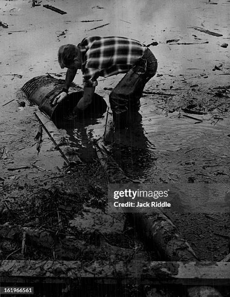 Floods - Denver; Jim Fuljham, an employe of Asphalt paving co., works to keep a sump pump clear of debris during pumping out of water on the valley...