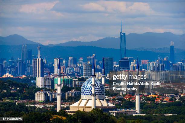 the sultan salahuddin abdul aziz mosque in selangor malaysia with clear view of the four skyscrapers of malaysia in the background - estado de selangor fotografías e imágenes de stock