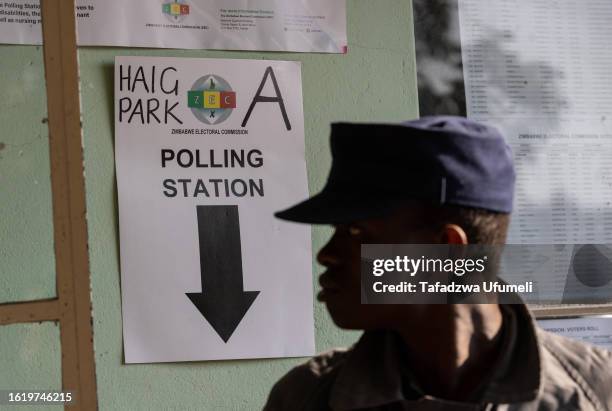 Police officer stands at an entrance controlling a queue at a polling station on August 24 in Harare, Zimbabwe. Against a backdrop of one of the...