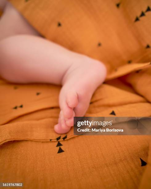 baby's foot on a yellow muslin swaddle. - atopic eczema stock pictures, royalty-free photos & images