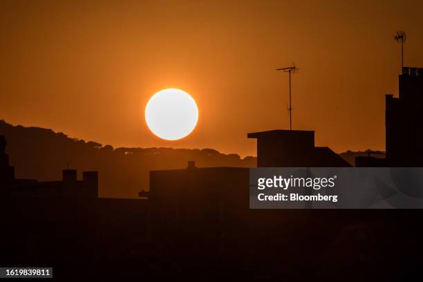 The sun sets beyond residential rooftops in Mataro, Spain, on Wednesday, Aug. 23, 2023. Heatwaves may "reduce Southern Europe's attractiveness as a...
