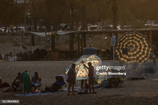 Beachgoers erect a sun parasol on the beach during high temperatures in Mataro, Spain, on Wednesday, Aug. 23, 2023. Heatwaves may "reduce Southern...