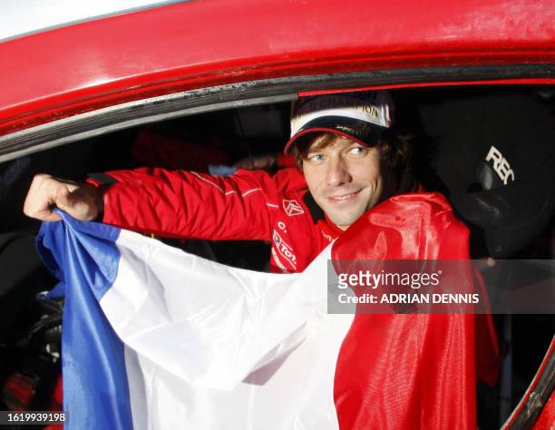 Citroen driver Sebastien Loeb, of France holds the tricolor inside his rally car after the podium ceremony after securing the World Rally...