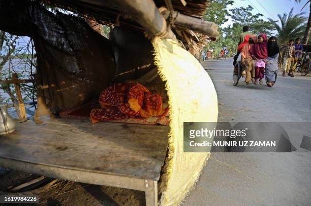 Displaced Bangladeshi villager offers prayers in a makeshift dwelling beside a road on the outskirts of Khulna some 400kms from Dhaka on May 31 after...