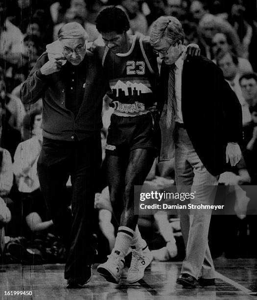 Special For Denver Post--Denver's T. R. Dunn is helped from the floor by Bob Chopper Traviligni, the trainer, and team doctor after he injured his...
