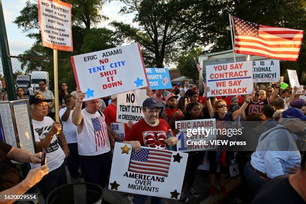 People attend a protest against the "tent city" for migrants at Creedmoor Psychiatric Center on August 16, 2023 in the Queens borough of New York...
