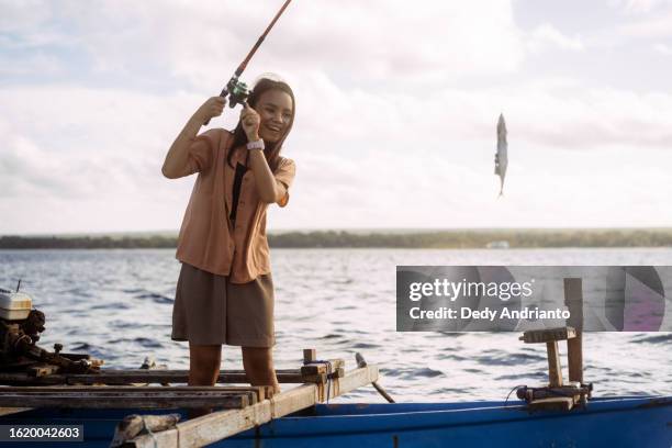 beautiful young asian woman learning to fish with fishing rod from local fisherman - celebes stock pictures, royalty-free photos & images