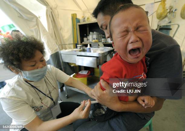 Boy cries as he receives an injection at a field hospital set up by the Chinese and German Red Cross societies in an earthquake-hit city of...