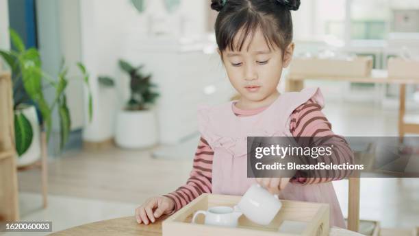 preschool mixed girl pouring water in jar, wet pouring activity, practical life skill, preliminary exercises in montessori education school - qualifying school stock pictures, royalty-free photos & images