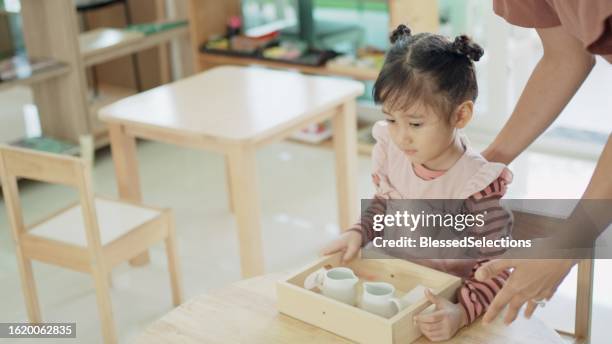 preschool girl getting ready for wet pouring activity, practical life skill, - qualifying school stock pictures, royalty-free photos & images