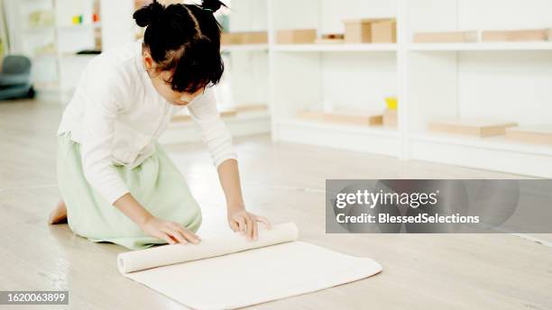 mixed elementary girl rolling mat, preliminary task in montessori education school - qualifying school stock pictures, royalty-free photos & images