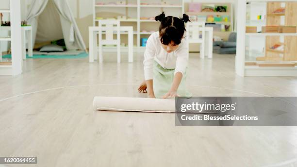 mixed elementary girl rolling mat, preliminary task in montessori education school - qualifying school stock pictures, royalty-free photos & images