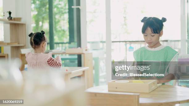 elementary mixed girl eating banana at table - qualifying school stock pictures, royalty-free photos & images