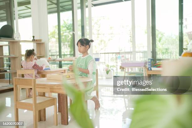 elementary mixed girl eating banana at table - qualifying school stock pictures, royalty-free photos & images