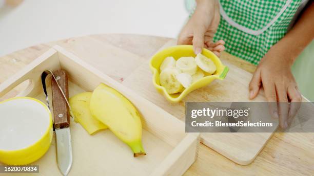 elementary mixed girl eating banana at table - qualifying school stock pictures, royalty-free photos & images