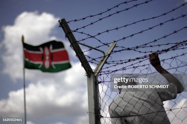 Steve a Kenyan man who immigrated to Nairobi from his home in central Kenya in search for a better future holds on to a fence as he watches the 12...