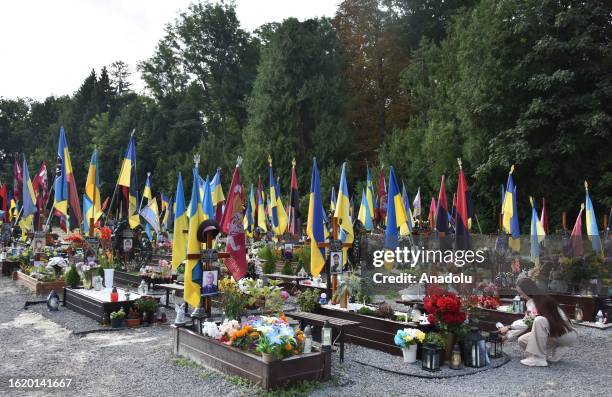 Woman places candles near the grave of Ukrainian soldier killed in the Russian-Ukrainian war during Ukraine's 32nd anniversary of Independence Day at...