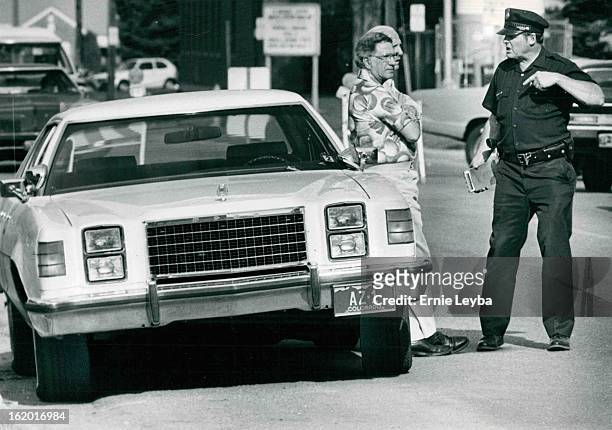 City Councilman Larry Perry Leans On Car As Policeman James 'Buster' Snider Talks With Him; Perry, who is struggling for re-election on May 15, has...