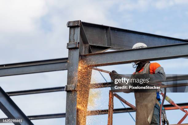 construction worker in lifting platform machine using an oxy-acetylene torch cutting the steel frame. - crane lifting equipment - fotografias e filmes do acervo