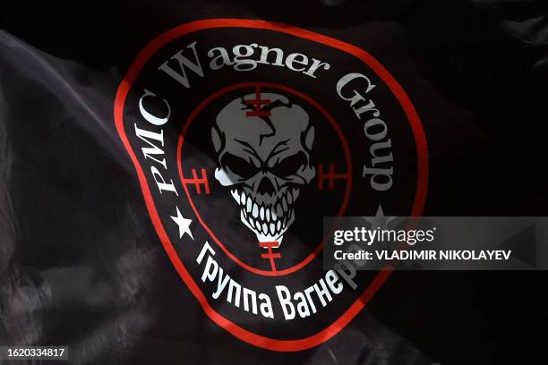 This photograph taken on August 24 shows a flag bearing the logo of private mercenary group Wagner as it flutters in the wind at a makeshift memorial...
