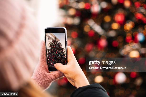 young woman taking picture of christmas tree with smart phone - white glove phone stock pictures, royalty-free photos & images