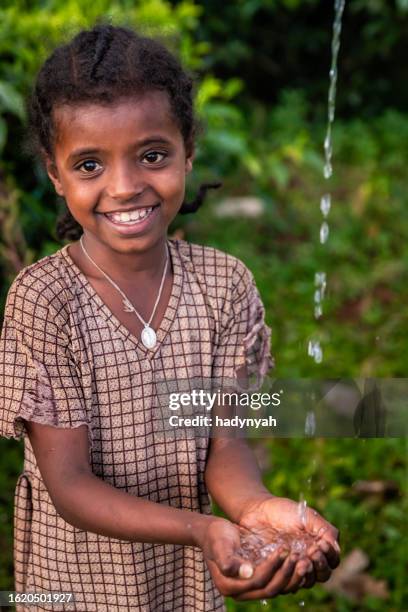 african little girl drinking fresh water, east africa - ethiopische etniciteit stockfoto's en -beelden