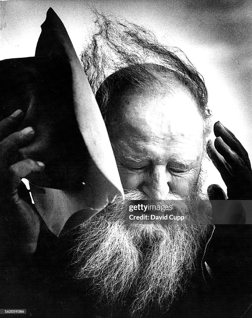 1974, AUG 13 1974, AUG 22 1974; Korczak Ziolkowski uses his hat to protect himself from the wind on