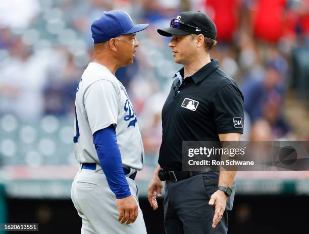 Dave Roberts of the Los Angeles Dodgers talks with umpire Mark Wegner as the tarp is pulled during the ninth inning against the Cleveland Guardians...