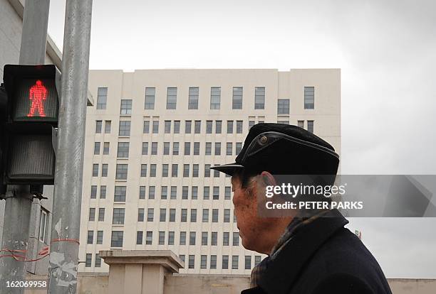 Man walks past a 12-storey building alleged in a report on February 19, 2013 by the Internet security firm Mandiant as the home of a Chinese...