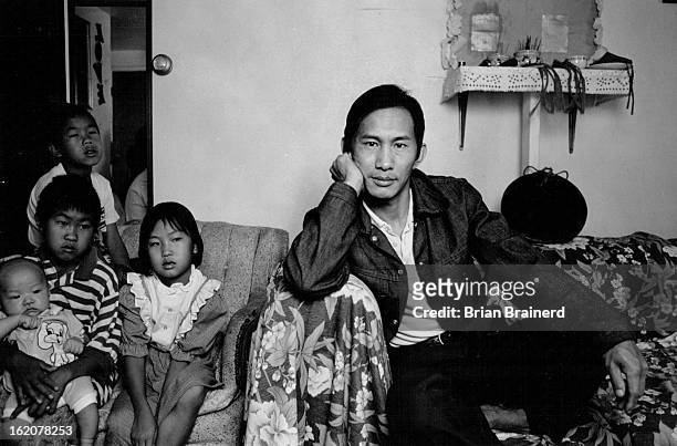 Hmong shaman Youa Truevang flanked by his family in their Westminster apartment. His ceremonial is, in the upper right -¬f photo.;