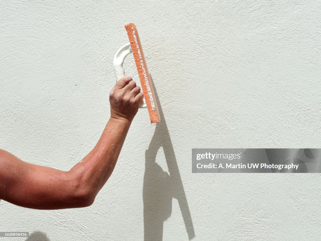 Closeup hand of worker plastering white cement at wall for building house