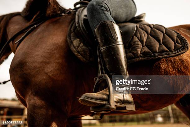 niedriger ausschnitt einer frau, die auf einer ranch reitet - steigbügel stock-fotos und bilder