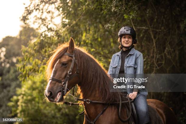 portrait of a young woman horseback riding on a stable - riding animals stock pictures, royalty-free photos & images