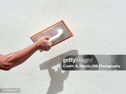 closeup hand of worker plastering white cement at wall for building house