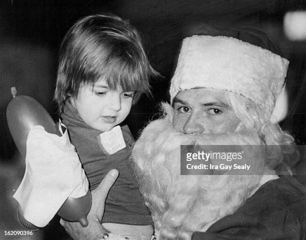 Party Time; A young airman dressed as Santa Claus makes friends with Bobby Mooney, right, during the Lowry Air Force Base Christmas party for Head...
