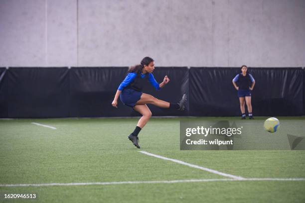 female teenager kicking a football at full strength - penalty sport stock pictures, royalty-free photos & images