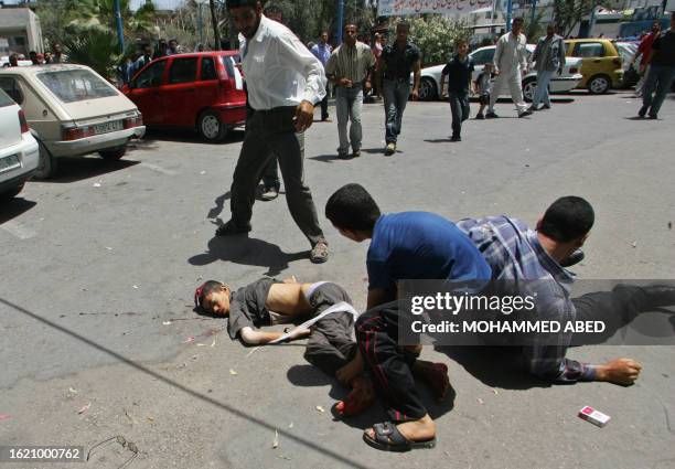 The body of a Palestinian boy killed in an Israeli air raid 13 June 2006 lies on the ground outside a hospital in Gaza City after the man carrying...