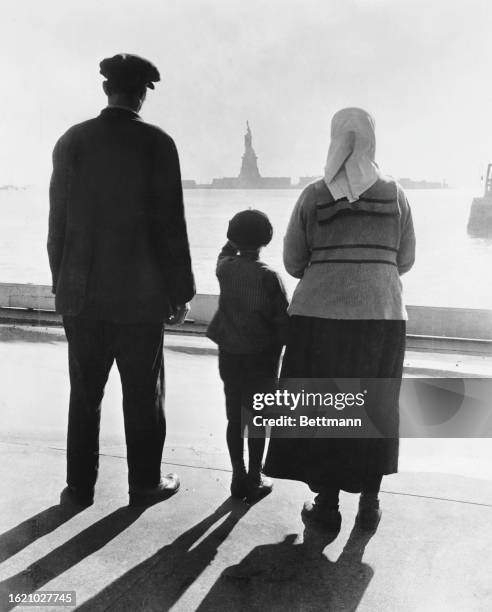 An immigrant family look at the Statue of Liberty from Ellis Island, New York/New Jersey, United States, circa 1940s.