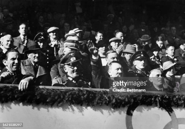 Adolf Hitler salutes as he watches Great Britain's Ice Hockey team - in between Dr. Paul Joseph Goebbels and General Werner Von Blomberg, gain a...