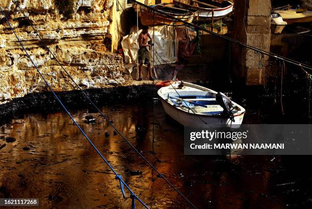 Lebanese fisherman pulls his boat at a small port in Beirut covered with a thick layer of oil spill, 25 August 2006. More than 15,000 tonnes of fuel...