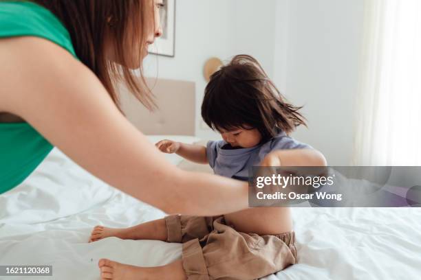 young asian mother helping her little girl to get dressed - getting dressed stock pictures, royalty-free photos & images