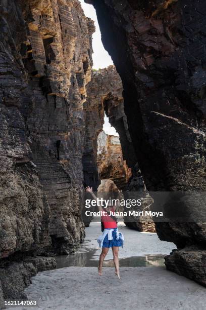 a woman jumping at "la playa de las catedrales" in ribadeo, lugo province. - provincia de lugo ストックフォトと画像