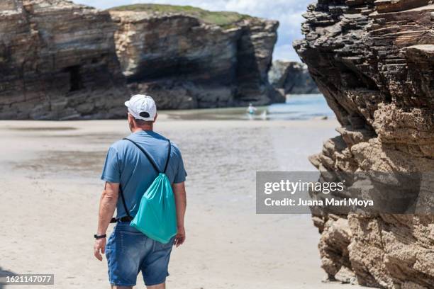 tourist exploring and contemplating "la playa de las catedrales" in ribadeo, province of lugo. - provincia de lugo ストックフォトと画像