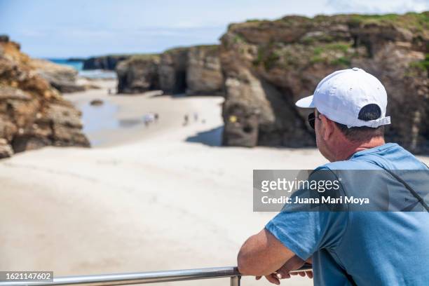 tourist exploring and contemplating "la playa de las catedrales" in ribadeo, province of lugo. - provincia de lugo ストックフォトと画像