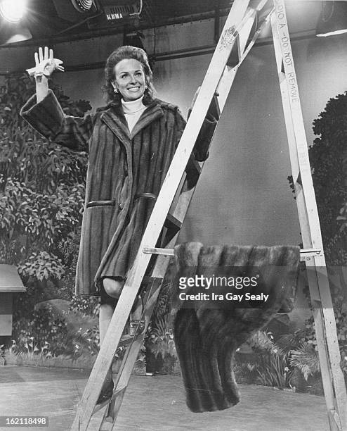 Mrs. Ringsby models Oleg Cassini-é+¦s natural-otter great-¼?-coat from Lloyd Furs. Emba mink stole, right on ladder, is $500, from J. C. Penney.;